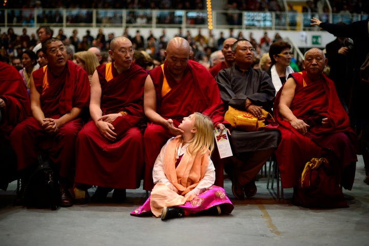 A girl sits by buddhist monks during a public meeting of the Tibetan spiitual leader, the Dalai Lama, after he was awarded the award of Minorities by province of Bolzano on April 11, 2013 in Trento. AFP PHOTO / OLIVIER MORIN (Photo credit should read OLIVIER MORIN/AFP/Getty Images)