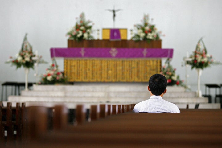 Kuala Lumpur, MALAYSIA: A lone churchgoer prays among empty benches at a cathedral in downtown Kuala Lumpur, 20 December 200