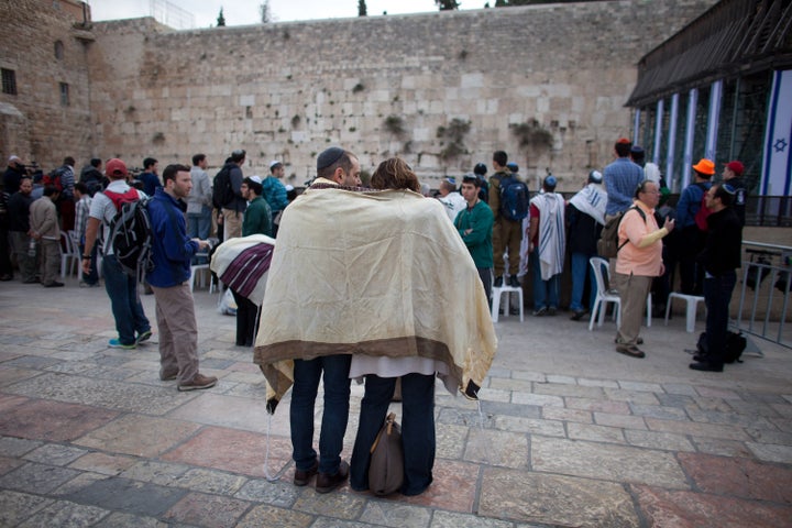 JERUSALEM, ISRAEL - APRIL 11: (ISRAEL OUT) A couple covered with a 'Tallit' (traditional Jewish prayer shawl) pray as member of the religious group 'Women of the Wall' pray at the Western Wall on April 11, 2013 in Jerusalem's Old City, Israel. Five members of the organisation 'Women of the Wall' were detained by police during the group's monthly prayer at the Western Wall, after covering themselves with prayer shawls in contradiction to the holy site's custom. (Photo by Uriel Sinai/Getty Images)