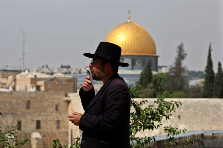 An Ultra-Orthodox Jewish man prays near the Western Wall in Jerusalem' s Old City backdropped by the Dome of the Rock Mosque,