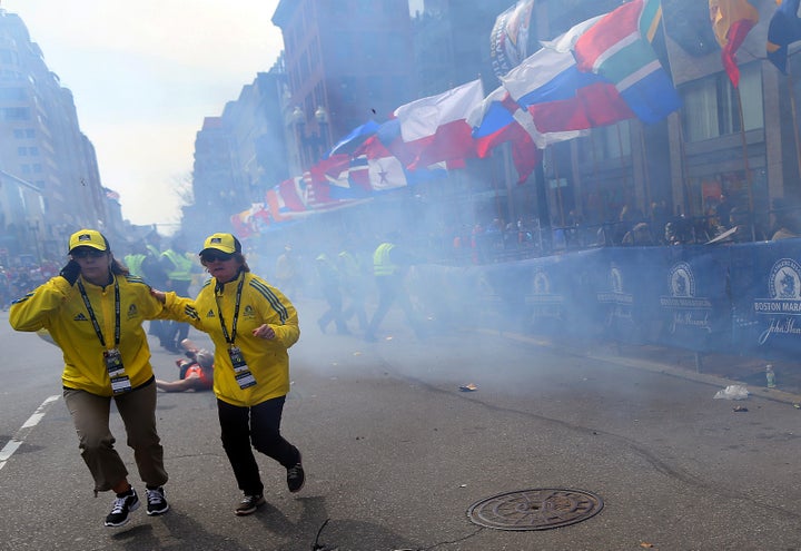 BOSTON - APRIL 15: Two officials run away from the first explosion, right, on Boylston Street at the 177th Boston Marathon, April 15, 2013. (Photo by John Tlumacki/The Boston Globe via Getty Images)