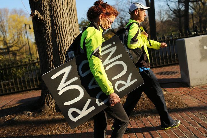 BOSTON, MA - APRIL 16: Claire Schaeffer Dufy walks with a sign she made to support her runner husband, Scott, near the scene of a twin bombing at the Boston Marathon on April 16, 2013 in Boston, Massachusetts. The twin bombings, which occurred near the marathon finish line, resulted in the deaths of three people while hospitalizing at least 128. The bombings at the 116-year-old Boston race, resulted in heightened security across the nation with cancellations of many professional sporting events as authorities search for a motive to the violence. (Photo by Spencer Platt/Getty Images)