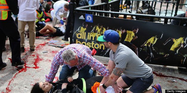 BOSTON - APRIL 15: (EDITOR'S NOTE: THIS IMAGE CONTAINS GRAPHIC CONTENT) Bystanders help an injured woman at the scene of the first explosion on Boylston Street near the finish line of the 117th Boston Marathon. (Photo by John Tlumacki/The Boston Globe via Getty Images)