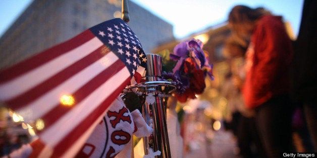 BOSTON, MA - APRIL 20: People gather at a makeshift memorial for victims near the site of the Boston Marathon bombings at the edge of the still-closed section of Boylston Street a day after the second suspect was captured on April 20, 2013 in Boston, Massachusetts. A manhunt for Dzhokhar A. Tsarnaev, 19, a suspect in the Boston Marathon bombing ended after he was apprehended on a boat parked on a residential property in Watertown, Massachusetts. His brother Tamerlan Tsarnaev, 26, the other suspect, was shot and killed after a car chase and shootout with police. The bombing, on April 15 at the finish line of the marathon, killed three people and wounded at least 170. (Photo by Mario Tama/Getty Images)