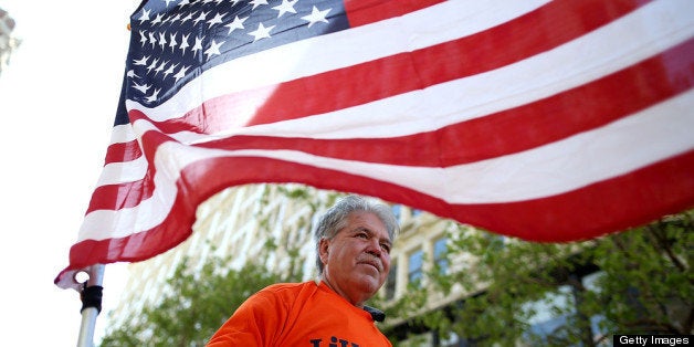 SAN FRANCISCO, CA - APRIL 10: A protestor carries an American flag as he rides in the back of a truck during an immigration reform demonstration on April 10, 2013 in San Francisco, California. Hundreds of immigration reform advocates held a rally outside of U.S. Sen. Dianne Feinstein's office and marched through downtown San Francisco to call on Congress to act on proposals that would grant a path to citizenship for an estimated 11 million of the nation's illegal immigrants. (Photo by Justin Sullivan/Getty Images)