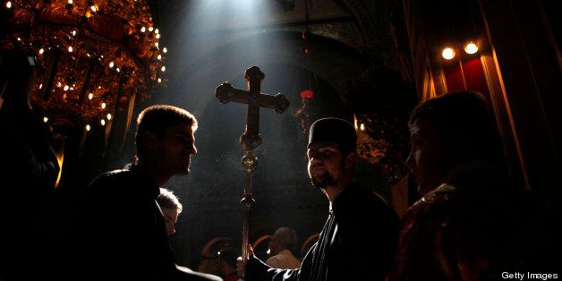 A Greek Orthodox altar boy holds up a ceremonial cross as a ray of light enters the church during the Orthodox Easter Sunday procession at the Church of the Holy Sepulchre in Jerusalem's Old City on April 15, 2012, to celebrate the resurrection of Jesus Christ. Christians traditionally believe the Church if the Holy Sepulchre is built on the site where Jesus Christ was crucified, buried and resurrected. AFP PHOTO/GALI TIBBON (Photo credit should read GALI TIBBON/AFP/Getty Images)