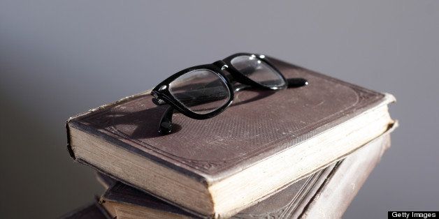 Nerdy black glasses on top of a pile of old books