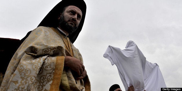 Greek Orthodox priests cover the body of the Christ with a white cloth during the Apokathelosis on April 2, 2010, marking the removal of Christ's body from the Cross forming a key part of Orthodox Easter, at the Church of the Dormition of the Virgin in Penteli, north Athens. Millions of Greeks flock to churches around the country this week to celebrate Easter, the country's foremost religious celebration. AFP PHOTO / Aris Messinis (Photo credit should read ARIS MESSINIS/AFP/Getty Images)