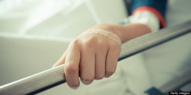 Image of boy in hospital's hand, with a band-aid.