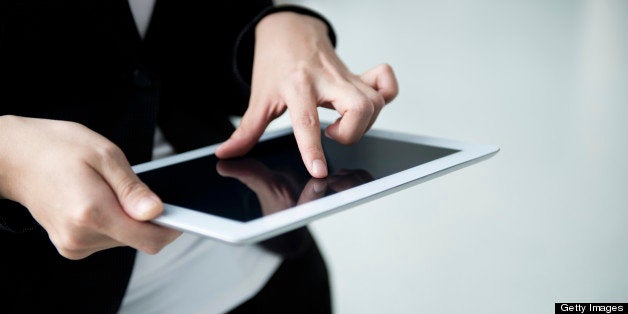 Young businesswoman holding and touching digital tablet.