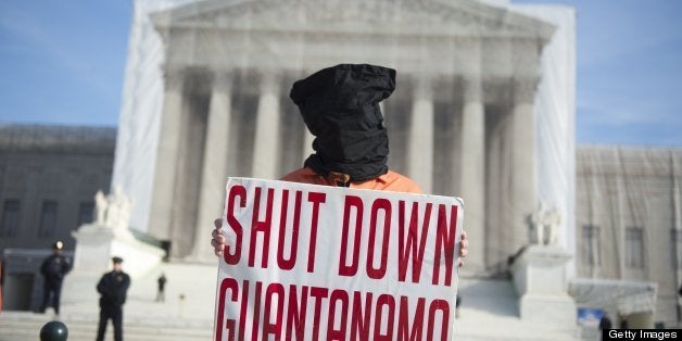 A protestor wears an orange prison jump suit and black hood on their head during protests against holding detainees at the military prison in Guantanamo Bay during a demonstration in front of the US Supreme Court in Washington, DC, on January 8, 2013. This weeks marks the 11th anniversary of the opening of the prison. AFP PHOTO / Saul LOEB (Photo credit should read SAUL LOEB/AFP/Getty Images)