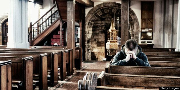 A man sitting, praying within St Michael's Anglican church in Lyme Regis, Dorset