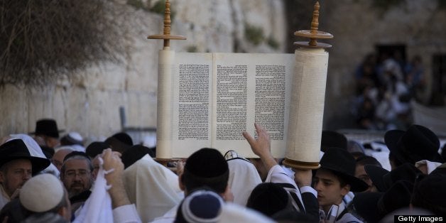 A Jewish man raises Torah scrolls during the Cohanim prayer (priest's blessing) during the Pesach (Passover) holiday at the Western Wall in the Old City of Jerusalem on March 28, 2013. Thousands of Jews make the pilgrimage to Jerusalem during the eight-day Pesach holiday, which commemorates the Israelites' exodus from slavery in Egypt some 3,500 years ago and their plight by refraining from eating leavened food products. AFP PHOTO / MENAHEM KAHANA (Photo credit should read MENAHEM KAHANA/AFP/Getty Images)