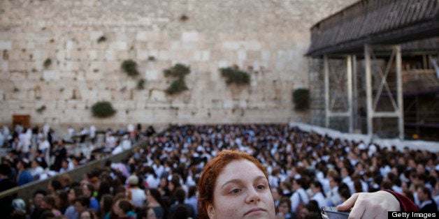 An Ultra Orthodox Jewish girl looks at members of the liberal eral Jewish religious group Women of the Wall on May 10, 2013 a