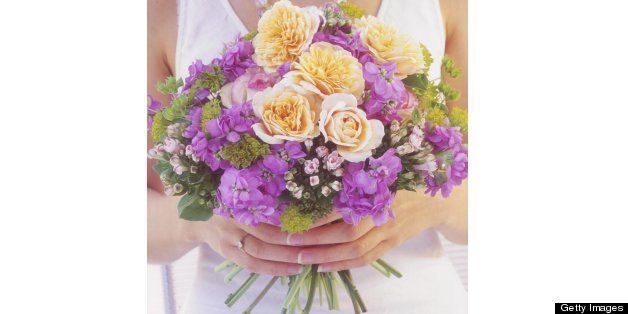 Woman in white dress holding yellow purple and green bouquet