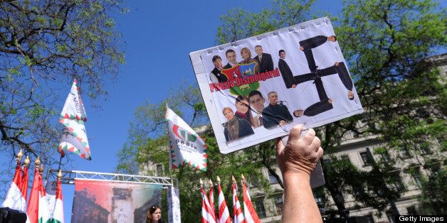 An anti-demonstrator lifts a home-made picture with a Swastika and photos of the party leaders and representatives of the nationalist party of the Hungarian Parliament, the JOBBIK's during a demonstration of the nationalist party in Budapest downtown, nearby the parliament building on May 4, 2013. Hundreds of Hungarians gathered Saturday in downtown Budapest for an anti-Zionist protest organised by the Jobbik party, just a day before a World Jewish Congress (WJC) meeting kicks off here AFP PHOTO / ATTILA KISBENEDEK (Photo credit should read ATTILA KISBENEDEK/AFP/Getty Images)