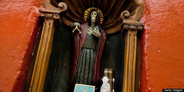 MEXICO CITY, MEXICO - MAY 27: A figurine of Santa Muerte (Saint Death) seen in a temple in the historical center of Mexico City, Mexico, on May 27, 2011. The religious cult of Santa Muerte, a syncretic fusion of Aztec death worship rituals and Catholic beliefs, has rapidly expanded. In the past decades, original Santa Muerte's followers (such as prostitutes, pickpockets and drug traffickers) have merged with thousands of ordinary Mexican Catholics. Although the Catholic Church considers the cult as devil worshipping, on the first day of every month, crowds of Santa Muerte's devotees fill the streets of Tepito. Holding skeletal figurines, they pray for power healing, protection and make petitions to ?La Santísima Muerte?. (Photo by Jan Sochor/Latincontent/Getty Images)