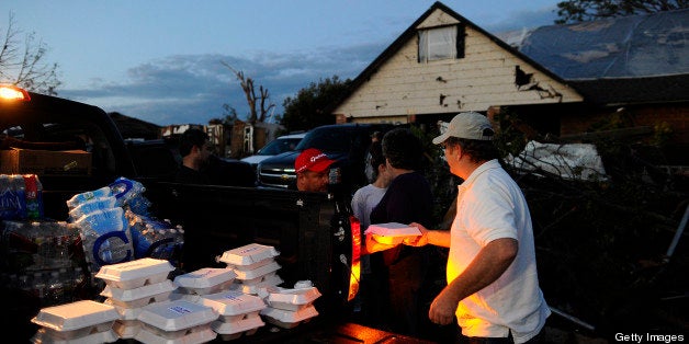 Derick Brock from Mercy Chefs distributes hot food to tornado victims at their devastated neighbourhood on May 21, 2013 in Moore, Oklahoma. Families returned to a blasted moonscape that had been an American suburb Tuesday after a monstrous tornado tore through the outskirts of Oklahoma City, killing at least 24 people. Nine children were among the dead and entire neighborhoods vanished, with often the foundations being the only thing left of what used to be houses and cars tossed like toys and heaped in big piles. AFP PHOTO/Jewel Samad (Photo credit should read JEWEL SAMAD/AFP/Getty Images)