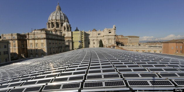 This picture taken on November 26, 2008 at the Vatican shows the solar panels covering the roof of the Paul VI audience hall with the Basilica of Saint Peter in the background (L). Some 1000 photovoltaic panels were installed on the football field-sized roof and should generate sufficient electricity to supply all heating, cooling and lighting of the 6300 seats? building, designed by architect Pier Luigi Nervi and completed in 1971. AFP PHOTO / ANDREAS SOLARO (Photo credit should read ANDREAS SOLARO/AFP/Getty Images)