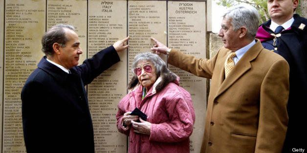 JERUSALEM, -: Italian Interior Minister Giuseppe Pisanu (L) and Police Commissioner Giovanni De Gennaro point at the name of Giovanni Palatucci on the Wall of Honor in the Garden of the Righteous, as they stand next to Elizabeth Quitt-Ferber, a holocaust survivor who was saved by Palatucci, during a ceremony honoring Palaticci as a Righteous Among the Nations at the Yard Vashem holocaust museum in Jerusalem, 10 February 2005. Palatucci saved the lives of thousands of Jews during the holocaust while serving as a police chief in northern Italy, giving them false identification and shelter. Palatucci who was caught by the Gestapo, sentenced, exiled and sent to the Dachau concentration camp where he died on February 10, 1945, at the age of 36. AFP PHOTO/GALI TIBBON (Photo credit should read GALI TIBBON/AFP/Getty Images)