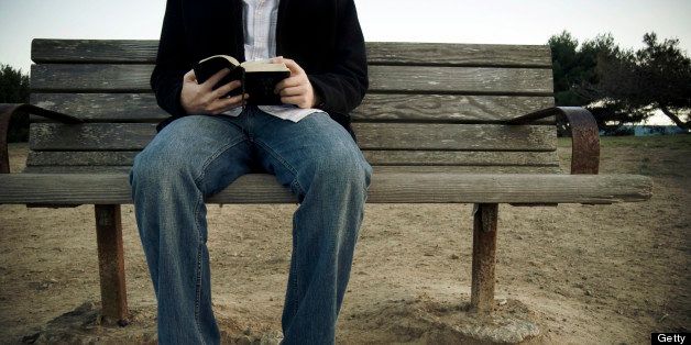 A man reading the Bible on a park bench