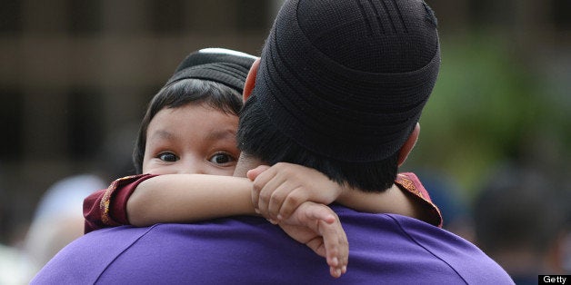 A young boy is held by his father as people attend prayers on Eid Al-Fitr at the Regent's Park Mosque in London on August 19, 2012. Muslims around the world celebrate Eid al-Fitr, marking the end of Ramadan, the Muslim calendar's ninth and holiest month during which followers are required to abstain from food, drink and sex from dawn to dusk. AFP PHOTO / ADEK BERRY (Photo credit should read ADEK BERRY/AFP/GettyImages)