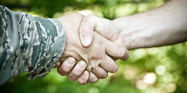 Military and civilian shake hands.