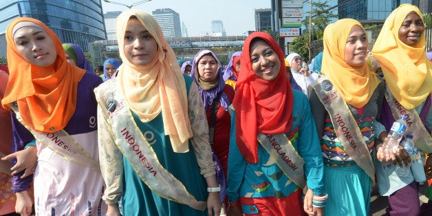 Contestants of the World Muslimah contest, Nanzin Sultana Liza (C, red headscarf) of Bangladesh, Obabiyi Aishah (R) of Nigeria and others from Indonesia take part in a fun walk in Jakarta on September 15, 2013. The Muslimah World contest to be held on September 18 in the Indonesian capital, Jakarta, is 'Islam's answer to Miss World', the pageant's founder Eka Shanti said on September 15. AFP PHOTO / ADEK BERRY (Photo credit should read ADEK BERRY/AFP/Getty Images)