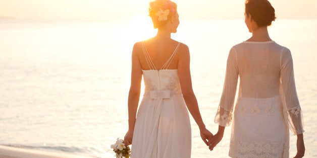 Same sex bridal couple holding hands at sunset