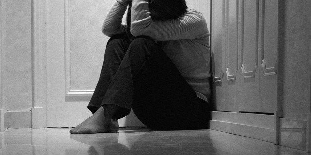 Woman sitting in corridor with head in hands, ground view (B&W)