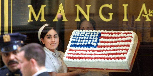 395293 01: A worker holds up an American flag cake at Mangia bakery in front of police officers standing guard during President Bush's visit to Wall Street October 3, 2001 in New York City. The American flag has rapidly appeared in storefronts nationwide following the September 11, 2001 terrorist attacks. (Photo by Mario Tama/Getty Images)