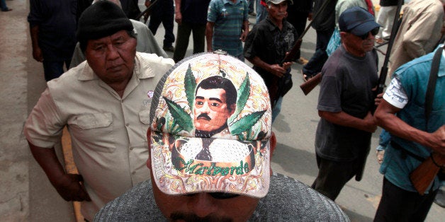 A community police member wearing a cap depicting Jesus Malverde --the saint of drug traffickers-- takes part in the March for Justice and Dignity, in Ayutla de los Libres, on March 2, 2013, in the southwestern State of Guerrero, Mexico. Hundreds of civilians armed with rifles, pistols and machetes decided to provide security for the communities of Guerrero, creating a vigilante force, saying gangs were committing robberies, kidnappings and murder. Guerrero, home to the Pacific resort town of Acapulco, has been one of the states hardest hit by Mexico's drug violence, which has left more than 70,000 people killed across the country since 2006. AFP PHOTO/Pedro Pardo (Photo credit should read Pedro PARDO/AFP/Getty Images)