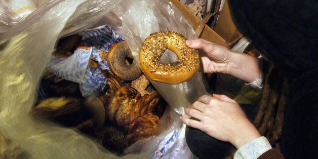 New York, UNITED STATES: A woman holds a bagel she found in a garbage bag of pastries and bagels outside a shop, 12 January, 2006, in the Greenwich Village section of New York. She is with an informal group called 'freegans' who use alternative strategies for living, including 'urban foraging' or 'dumpster diving' which involves rummaging through the garbage of retailers, residences, offices, and other facilities for useful goods. Freegan is a combination of 'free' and 'vegan', although many of the people are not strict vegetarians. AFP PHOTO/Stan HONDA (Photo credit should read STAN HONDA/AFP/Getty Images)