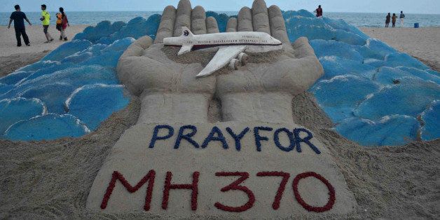 Beachgoers walk past a sand sculpture made by Indian sand artist Sudersan Pattnaik with a message of prayers for the missing Malaysian Airlines flight MH370 - which vanished from radar early on March 8 with ongoing search operations mounted by multiple nations taking place in the South China Sea, the Malacca Strait, and the Andaman Sea - at Puri beach, some 65 kilometers away from Bhubaneswar, on March 14, 2014. Malaysia denied March 12 that the hunt for a missing jet was in disarray, after the search veered far from the planned route and China said that conflicting information about its course was 'pretty chaotic'. AFP PHOTO/ ASIT KUMAR (Photo credit should read ASIT KUMAR/AFP/Getty Images)