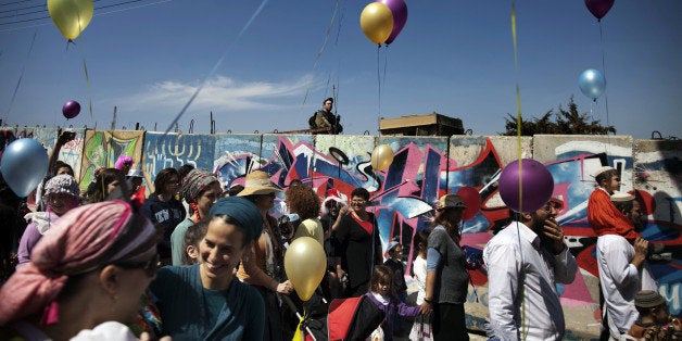 An Israeli settler stands guard as Jewish settlers celebrate the annual Purim parade on March 8, 2012, in the divided West Bank city of Hebron. Purim commemorates the salvation of the Jews from the ancient Persians as described in the biblical book of Esther. AFP PHOTO/MENAHEM KAHANA (Photo credit should read MENAHEM KAHANA/AFP/Getty Images)