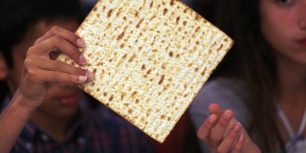 MIAMI BEACH, FL - MARCH 25: Omri Brandes (L) and Nitzan Brandes eat matzo during a community Passover Seder at Beth Israel