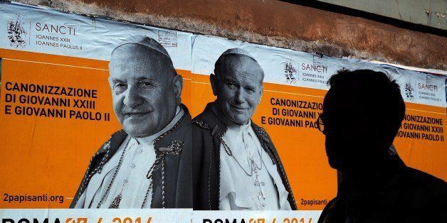 A man walks past posters announcing the double canonisation of Popes John Paul II and John XXIII on April 24, 2014 in Rome. Late popes John Paul II and John XXIII will be made saints at an unprecedented joint ceremony on April 27, 2014 in a bid to unite Catholic conservatives and liberals. The canonisations of two popular popes are set to bring hundreds of thousands of pilgrims to Rome. AFP PHOTO/ Filippo MONTEFORTE (Photo credit should read FILIPPO MONTEFORTE/AFP/Getty Images)