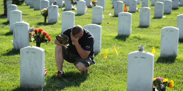 ARLINGTON, VA - MAY 25: Mike Sunderhaus of Belair, Maryland, becomes emotional as he visits the grave site of his friend, U.S. Marine Corps Lance Corporal Jeremiah E. Savage who was killed in 2004 during Operation Iraqi Freedom, at Arlington National Cemetery May 25, 2014 in Arlington, Virginia. Americans across the nation observe the Memorial Day this weekend to remember the men and women who died while serving in the U.S. military. (Photo by Alex Wong/Getty Images)