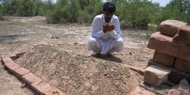 Pakistani resident Mohammad Iqbal prays at the grave of his wife Farzana Parveen, who was beaten to death with bricks by her father and other family members for marrying a man of her own choice, in Chak 367 some 40 kms from Faisalabad on May 30, 2014. Pakistani police investigating the murder of a woman bludgeoned to death outside a court have arrested four men, a senior officer said, as her husband said he wanted her killers to 'die in pain'. Farzana Parveen was killed on May 27 outside the High Court in the eastern city of Lahore by more than two dozen attackers armed with bricks, including numerous relatives, for marrying against her family's wishes. AFP PHOTO/Aamir QURESHI (Photo credit should read AAMIR QURESHI/AFP/Getty Images)