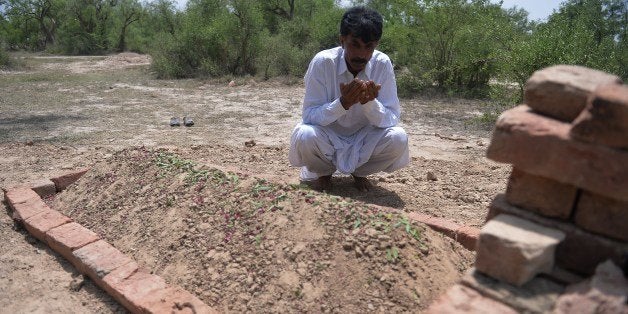 Pakistani resident Mohammad Iqbal prays at the grave of his wife Farzana Parveen, who was beaten to death with bricks by her father and other family members for marrying a man of her own choice, in Chak 367 some 40 kms from Faisalabad on May 30, 2014. Pakistani police investigating the murder of a woman bludgeoned to death outside a court have arrested four men, a senior officer said, as her husband said he wanted her killers to 'die in pain'. Farzana Parveen was killed on May 27 outside the High Court in the eastern city of Lahore by more than two dozen attackers armed with bricks, including numerous relatives, for marrying against her family's wishes. AFP PHOTO/Aamir QURESHI (Photo credit should read AAMIR QURESHI/AFP/Getty Images)