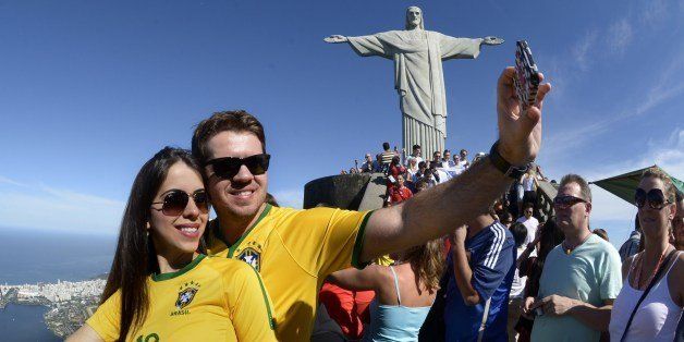 A couple take a 'selfie' in front of the statue of Christ the Redeemer atop Corcovado hill in Rio de Janeiro, Brazil, on June 14, 2014. AFP PHOTO / JUAN MABROMATA (Photo credit should read JUAN MABROMATA/AFP/Getty Images)