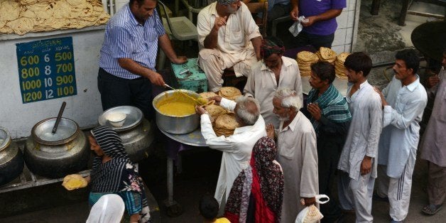 Pakistani Muslim devotees receive Iftar food as they break their fast during the holy fasting month of Ramadan in Lahore on June 30, 2014. The fasting month of Ramadan is sacred for the world's estimated 1.6 billion Muslims because it is during that month that tradition says the Koran was revealed to the Prophet Mohammed. The faithful fast from dawn to dusk, and abstain from eating, drinking, smoking and having sex during that time as they strive to be more pious and charitable. AFP PHOTO / Arif ALI (Photo credit should read Arif Ali/AFP/Getty Images)