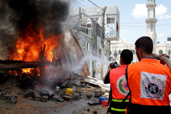 Palestinian firefighters extinguish a fire that broke out after an Israeli air strike hit a car in Gaza City, Gaza on July 14