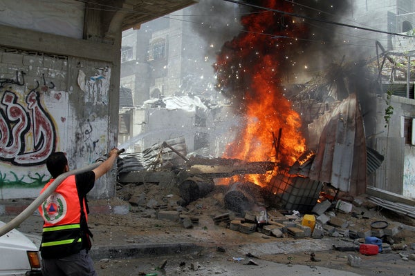 Palestinian firefighters extinguish a fire that broke out after an Israeli air strike hit a car in Gaza City, Gaza on July 14