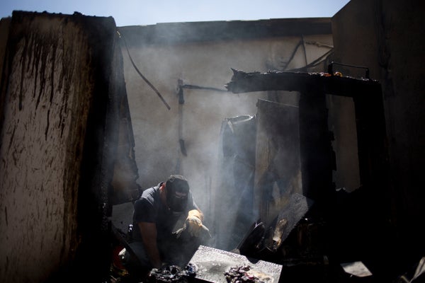 An Israeli police sapper surveys a damaged house after a rocket fired by Palestinian militants hit in a kibbutz near the bord