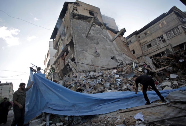 Palestinians cover the ruble of a destroyed house following an overnight Israeli missile strike in Gaza City Monday, July 14,