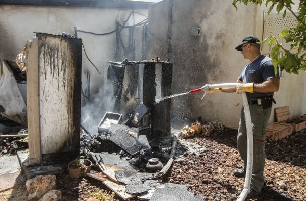 An Israeli bomb disposal expert extinguishes the fire following a rocket attack  by Palestinian militants from the Gaza Strip