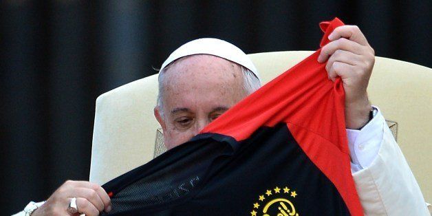 Pope Francis holds a jersey offered to him by German altar boys and girls during an open-air meeting in Saint Peter's Square at the Vatican on August 5, 2014. AFP PHOTO / ALBERTO PIZZOLI (Photo credit should read ALBERTO PIZZOLI/AFP/Getty Images)