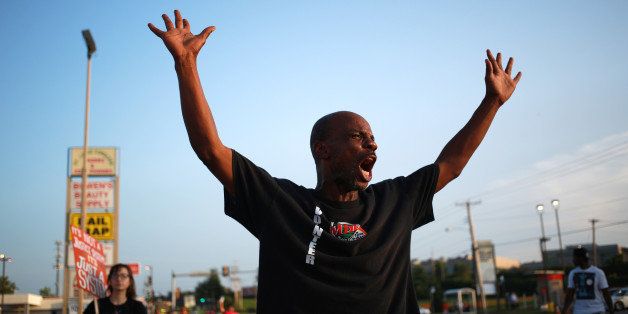 A protestor is seen standing with his arms raised above his head during demonstrations in Ferguson, Missouri, U.S., on Wednesday, Aug. 20, 2014. The Missouri grand jury that began considering evidence in the police killing of an unarmed man won't decide whether to indict Ferguson police officer Darren Wilson until October 'at the earliest, a spokesman for the local prosecutor said. Photographer: Luke Sharrett/Bloomberg via Getty Images