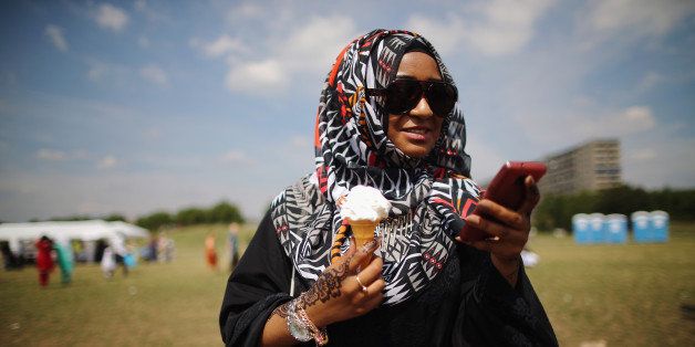LONDON, ENGLAND - AUGUST 08: A Muslim woman enjoys an ice-cream during an Eid celebration fun fair in Burgess Park on August 8, 2013 in London, England. The Muslim holiday Eid marks the end of 30 days of dawn-to-sunset fasting during the holy month of Ramadan. (Photo by Dan Kitwood/Getty Images)